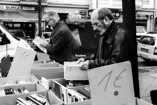 Black-and-white street photograph of men browsing secondhand books in Berlin